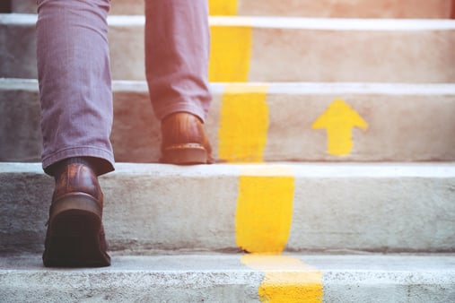 A man walking up stairs with a painted yellow line and arrow. The concept of growth. 
