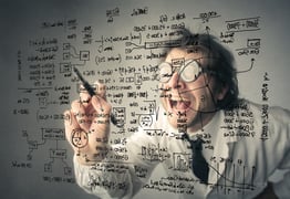 Person with glasses writing complicated formulas on glass