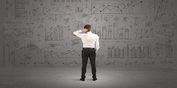 A young businessman standing in front of wall full of hand drawn calculations concep