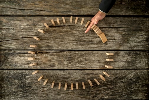 Businessman's hand is stopping the domino effect. Business concept