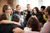 People standing in a circle embracing 
