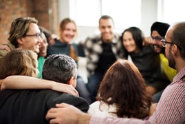 People standing in a circle embracing 