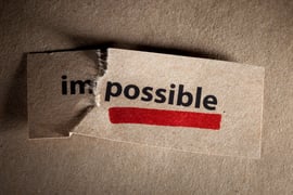 A piece of paper that says 'impossible' ripped in two, leaving one side to say 'im' and the other, underlined, reading 'possible.