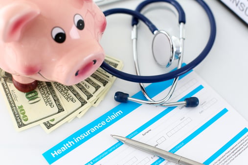 Money under the piggy bank, stethoscope with health insurance claim form