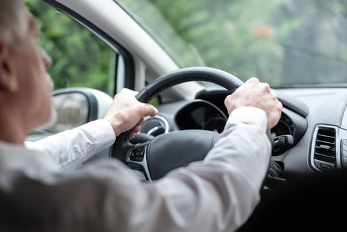 The concept of being in control and driving the sales process. A person with both hands on the wheel of a car. 