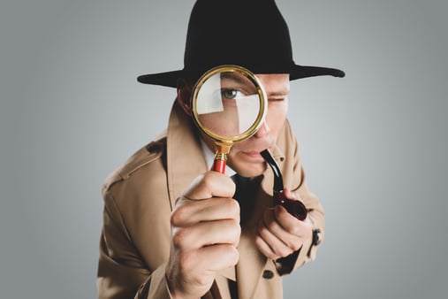 A man dressed like Sherlock Holmes smoking a pipe and holding a magnifying glass 