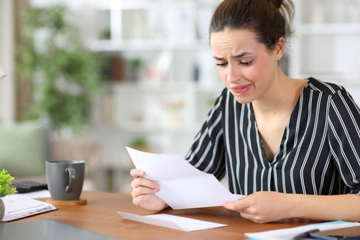 An employee or employer who is staring at a piece of paper and looks worried 
