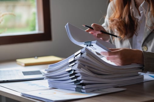 The concept of keeping up with compliance. A businessperson reviewing documents. 