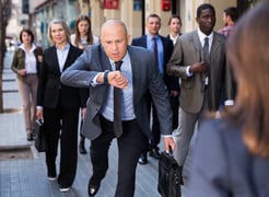 Stressed businessman checking his watch and running 