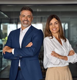 Employee benefits agency owners smiling standing back to back with their arms folded