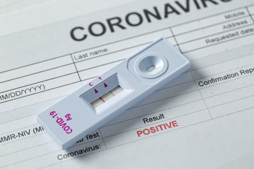 A COVID-19 test sitting on a positive COVID-19 form 