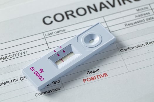 A COVID-19 test sitting on a positive COVID-19 form 