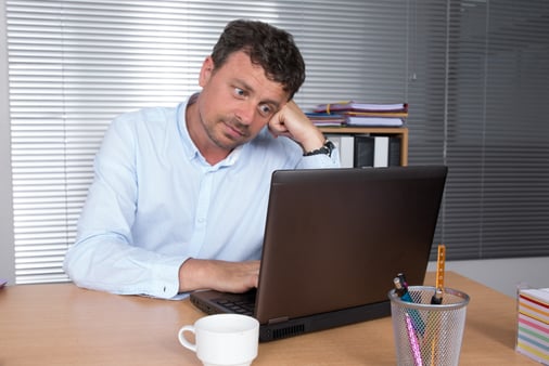 An insecure salesperson staring at their laptop, concept of imposter syndrome