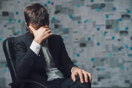 A worried salesperson with his head in his hand, representing repressed emotions