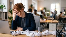 Burned out employee siting at her desk with her head in her hand