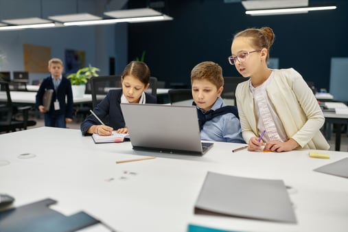 Children dressed in business clothes and working on a project together