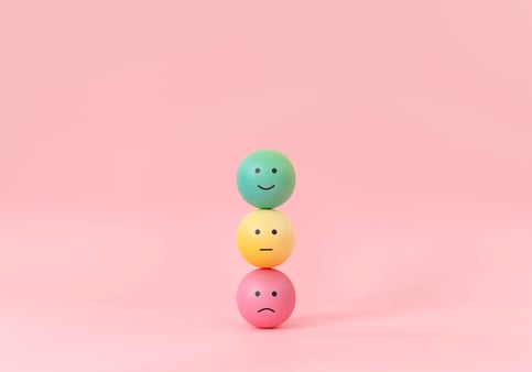 Three balls balanced on top of each other with various emotions on them 
