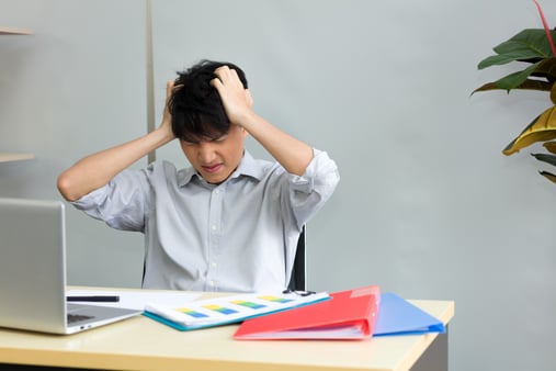 A frustrated, nervous, and unprepared man sitting at a desk