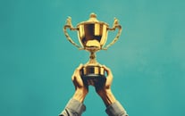 Two hands holding up a trophy 