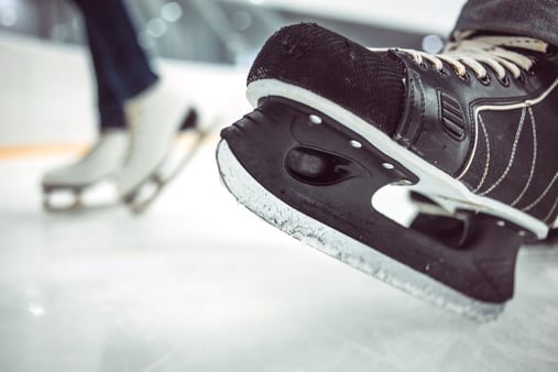 Men's hockey skates on an ice rink and skating toward a goal 