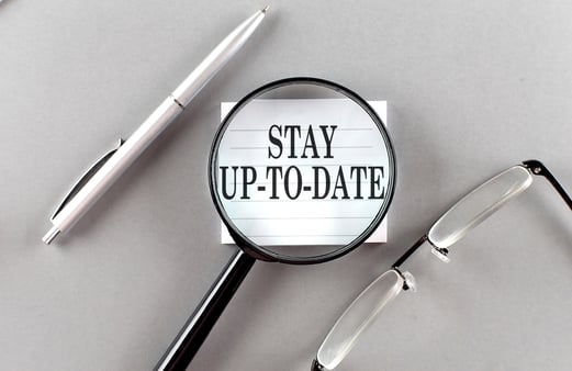 A magnifying glass magnifying words that say stay up to date 