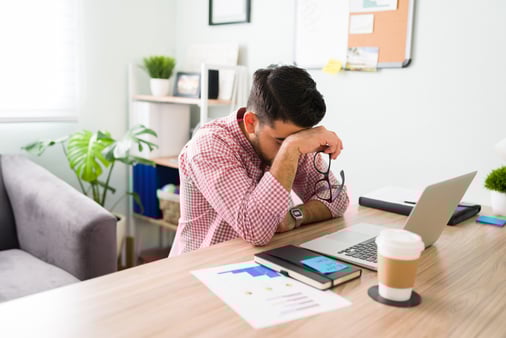 A salesperson with his head in his hand and stressed out over a situation