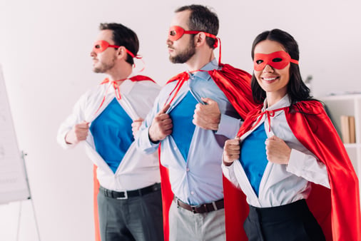 Three smiling business people dressed as superheroes