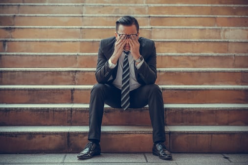 An emotional salesperson sitting on a set of bleachers