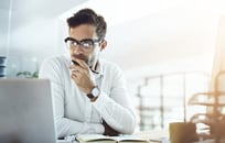 A businessperson sitting at their computer and thinking