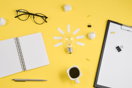 Concept of branding and brainstorming. Glasses, a lightbulb, and office tools on a yellow background. 