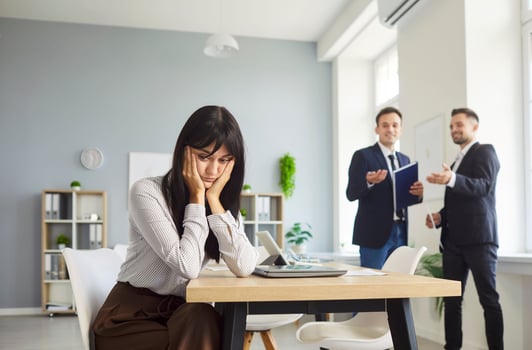 Woman being gossiped about by her coworkers
