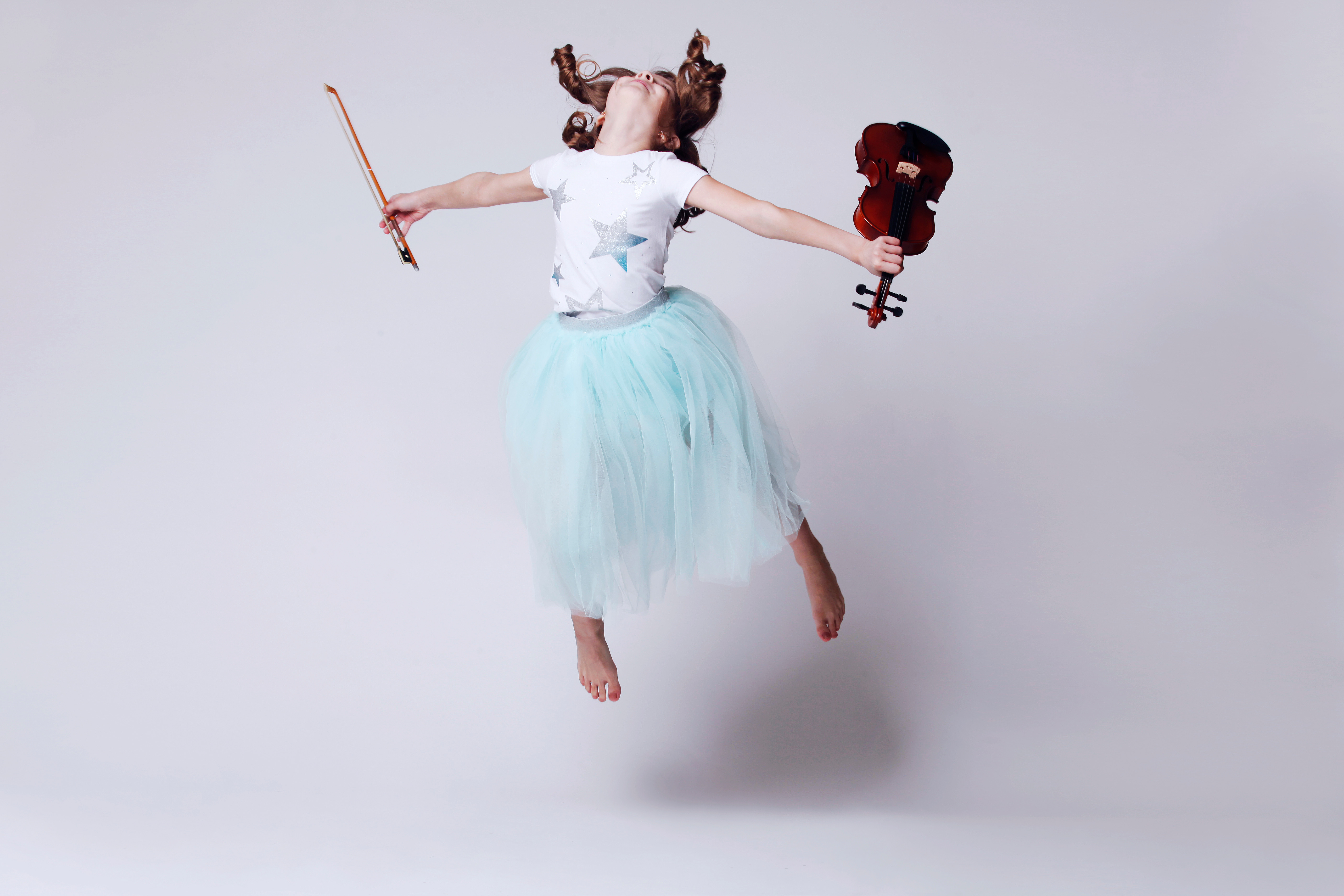 Little girl jumping with violin 