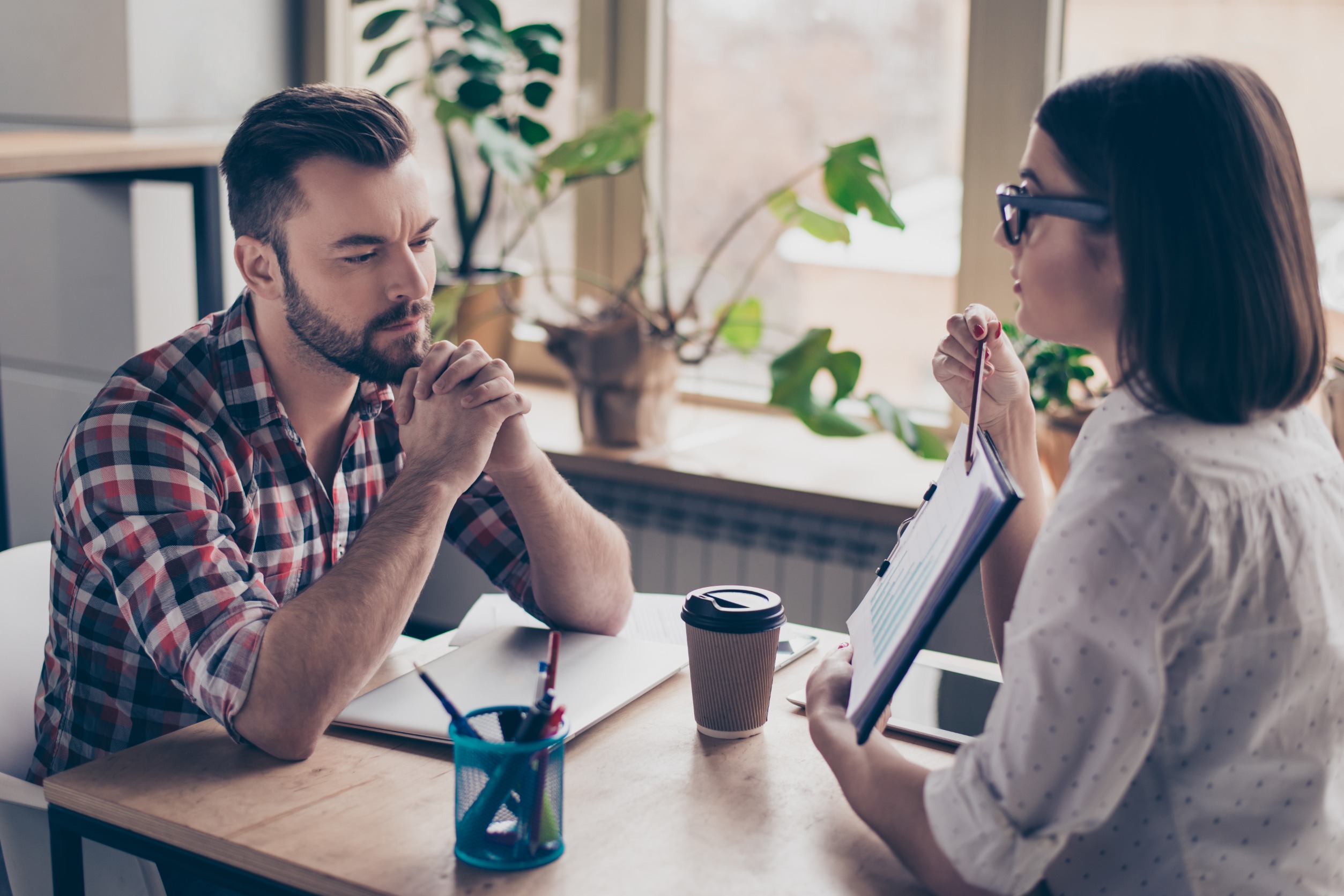 Two people sitting at a table discussing something 